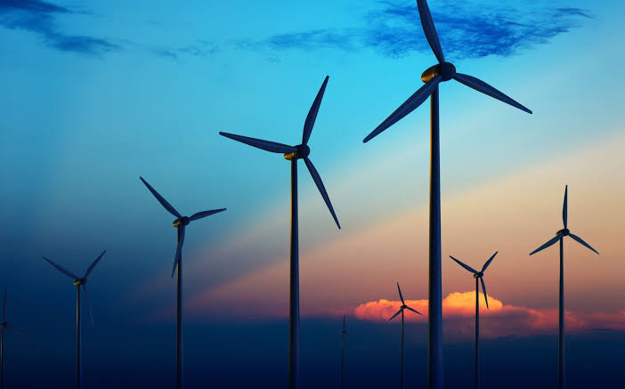 Wind turbines silhouetted against a dramatic sunset sky